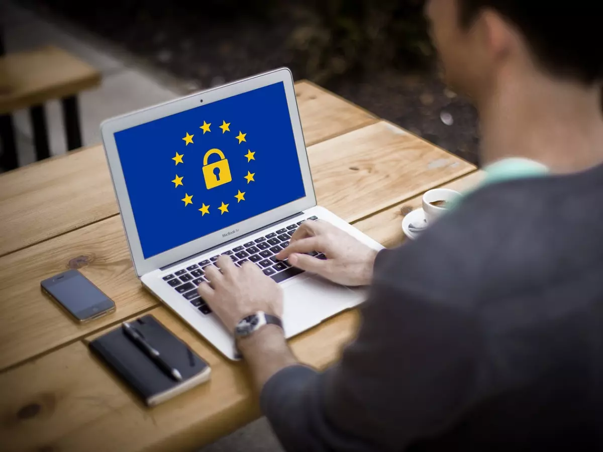 A person working on a laptop with the EU flag and a padlock on the screen.