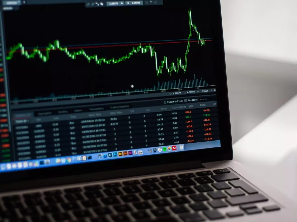 A laptop screen displaying a stock market graph with a sharp upward trend, indicating significant growth in the tech sector.