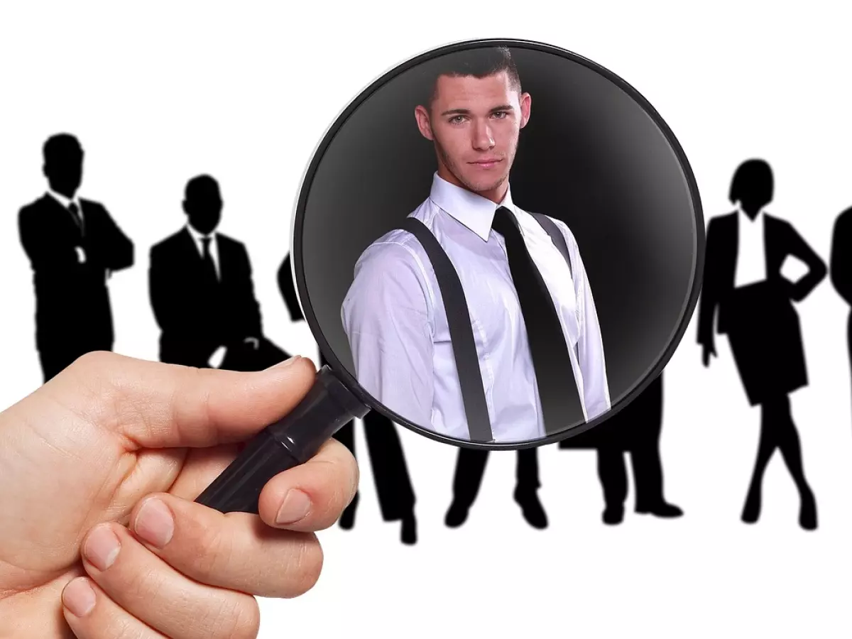 A man in a suit being looked at through a magnifying glass