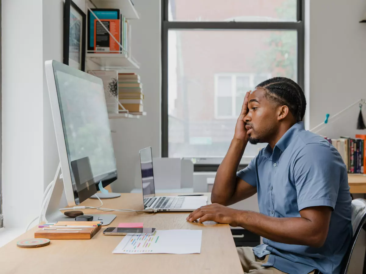 A person looking concerned while working on their computer in a home office.