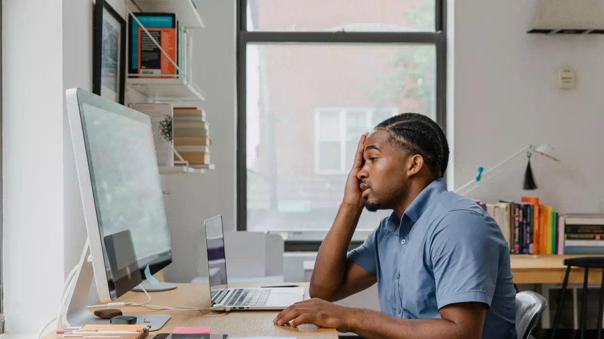 A person looking concerned while working on their computer in a home office.