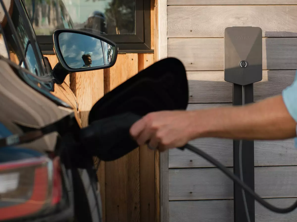 A person plugging in an electric vehicle with a charging cable. 