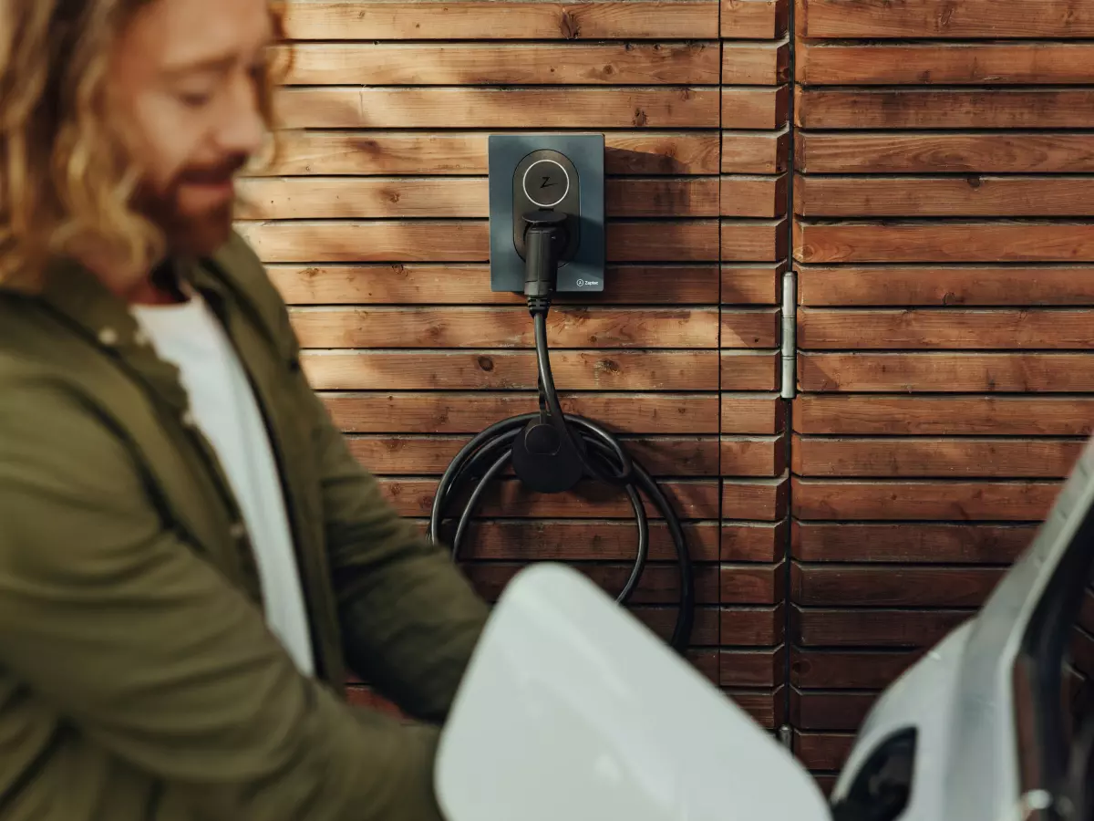 A man is charging an electric car at a charging station.