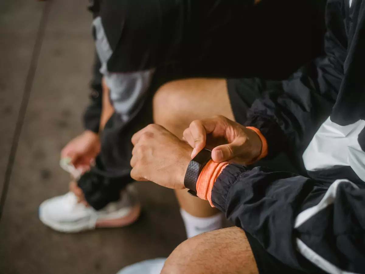 A person's hand adjusting an Apple Watch on their wrist. The focus is on the watch, which is the main subject of the image.