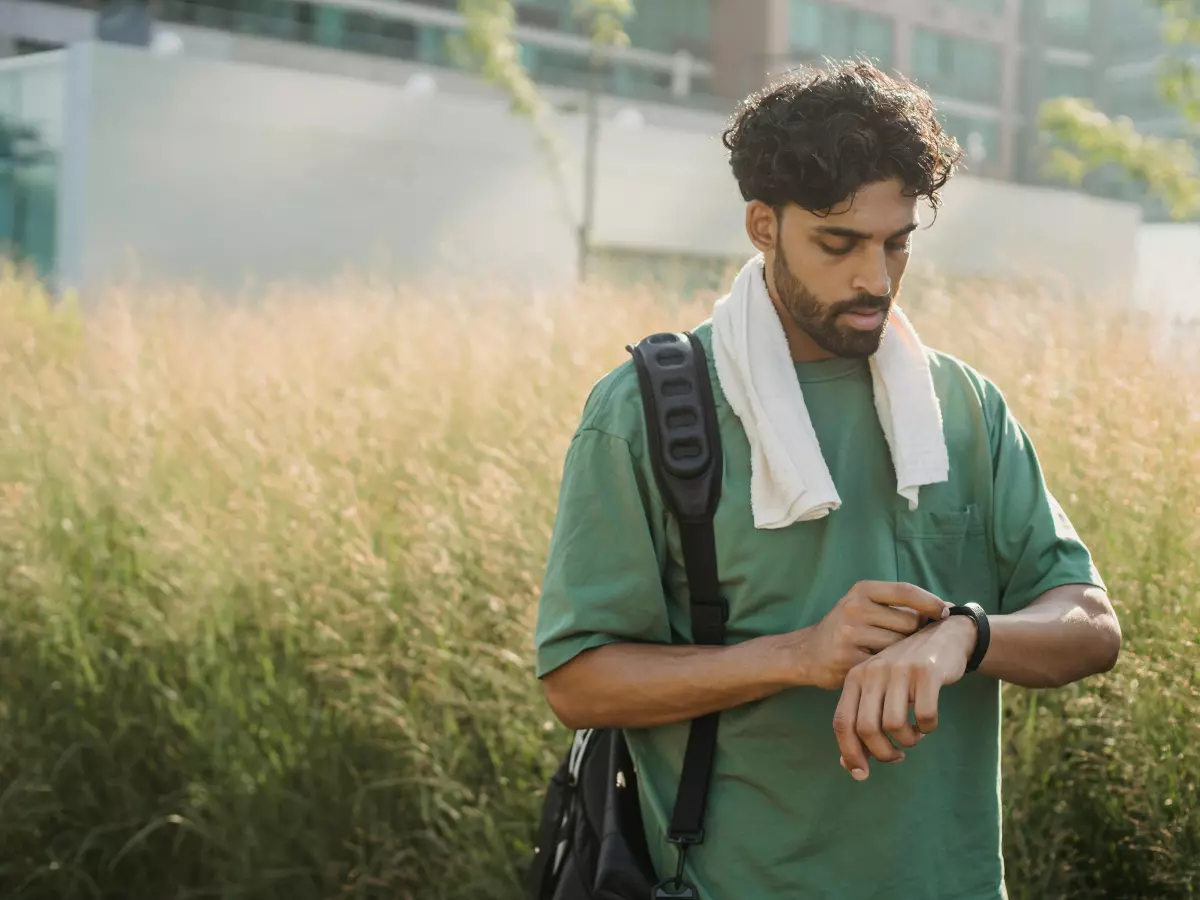 A man wearing a smartwatch while walking outdoors.