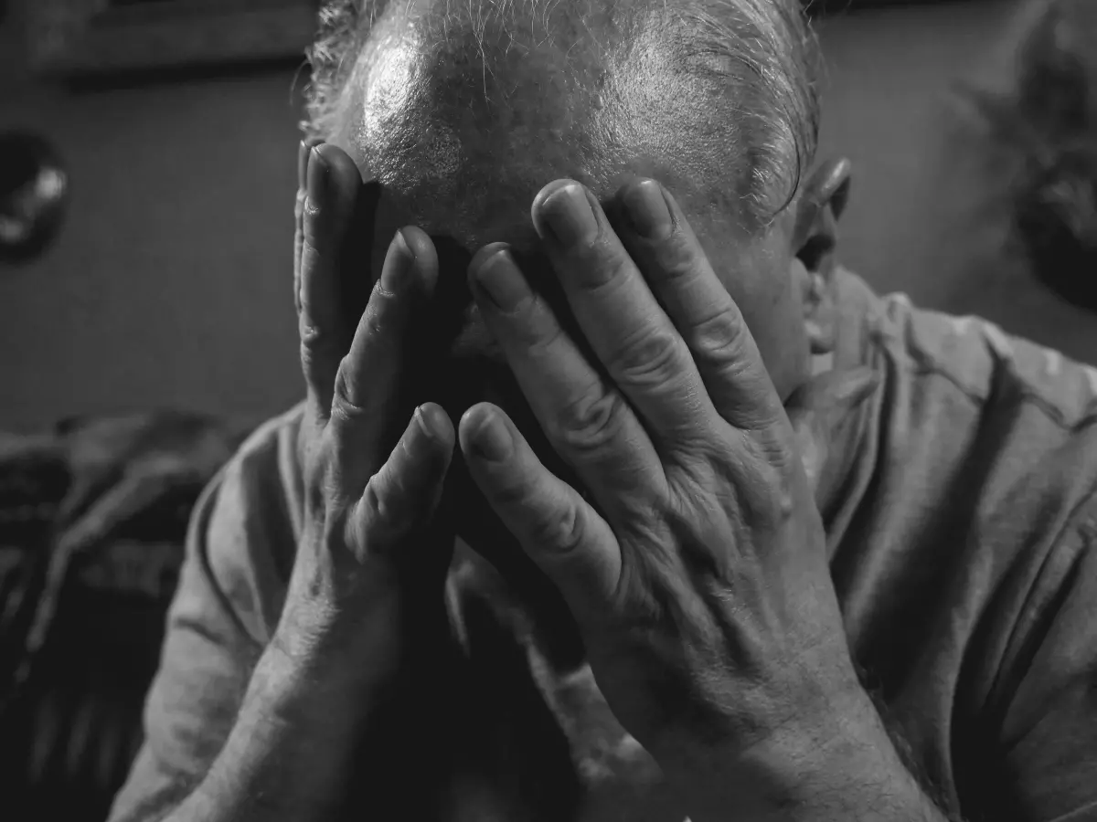 A person is sitting in a chair and has their head in their hands.