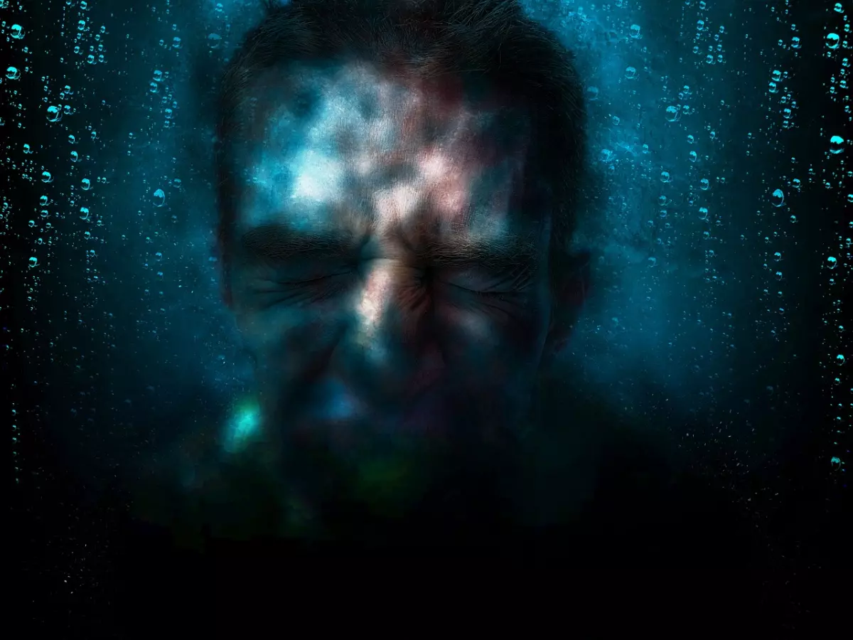 Close-up of a man's face obscured by water droplets and a swirling effect.