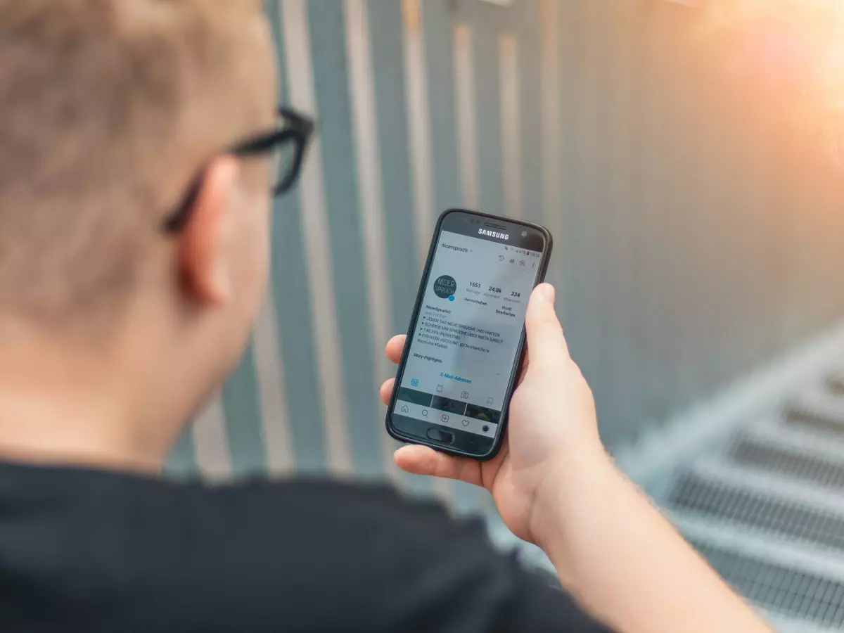 A person in a black shirt looking at a smartphone.