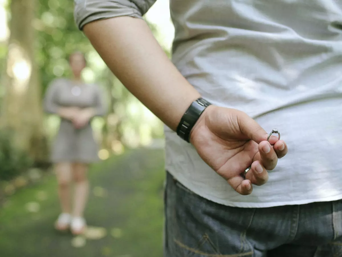 A man wearing a smartwatch on his wrist, with a woman standing in the background.