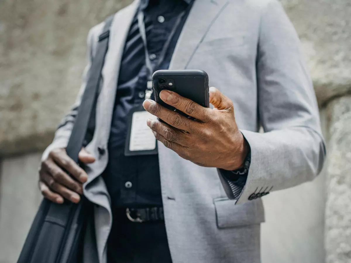 A man in a suit checks his phone while walking in the city