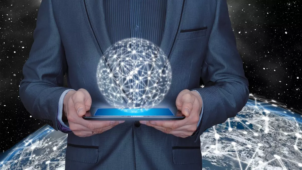 A man in a suit is holding a tablet with a holographic sphere of a network above it. The background shows the Earth with a similar network on its surface. The man is standing in front of a dark, starry sky.