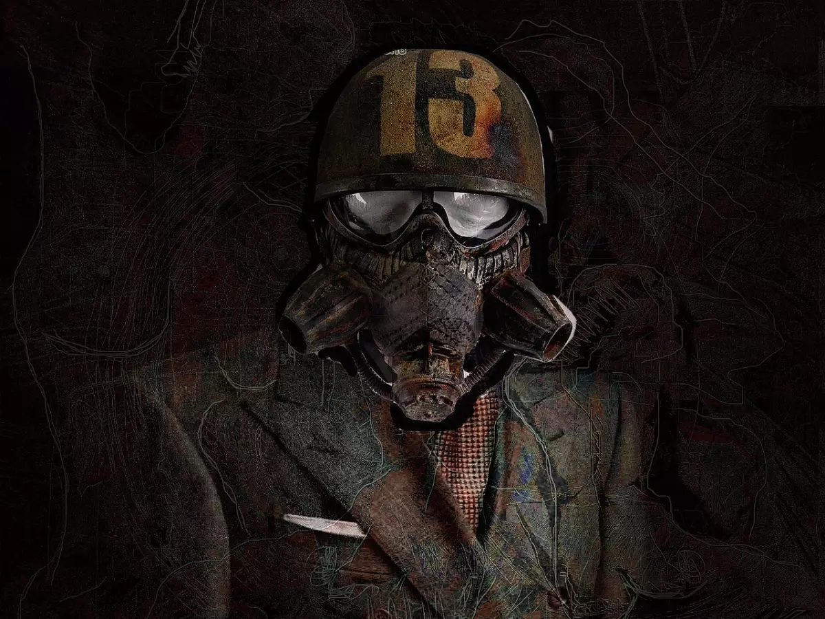 A soldier in a helmet and gas mask stands in a suit, with a dark background.