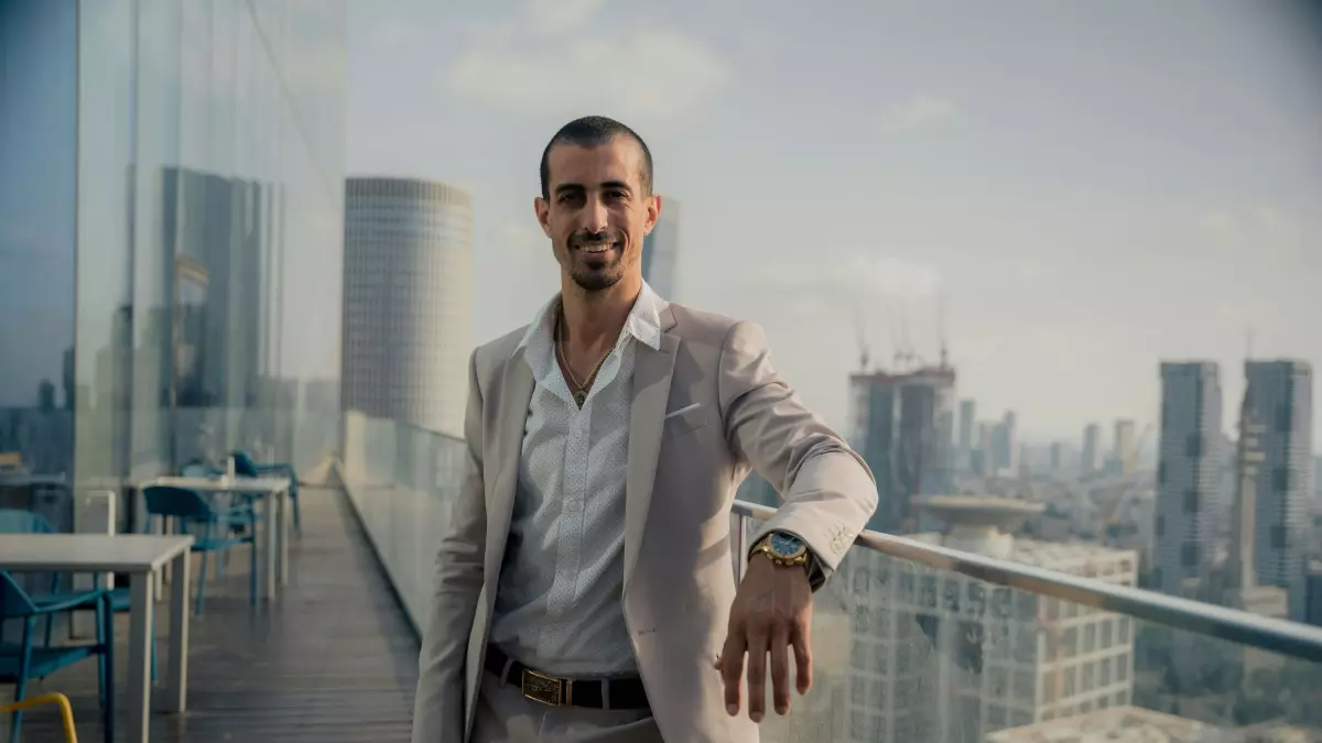 A confident-looking man in a suit stands on a rooftop overlooking a modern city skyline. He appears to be in a position of power.