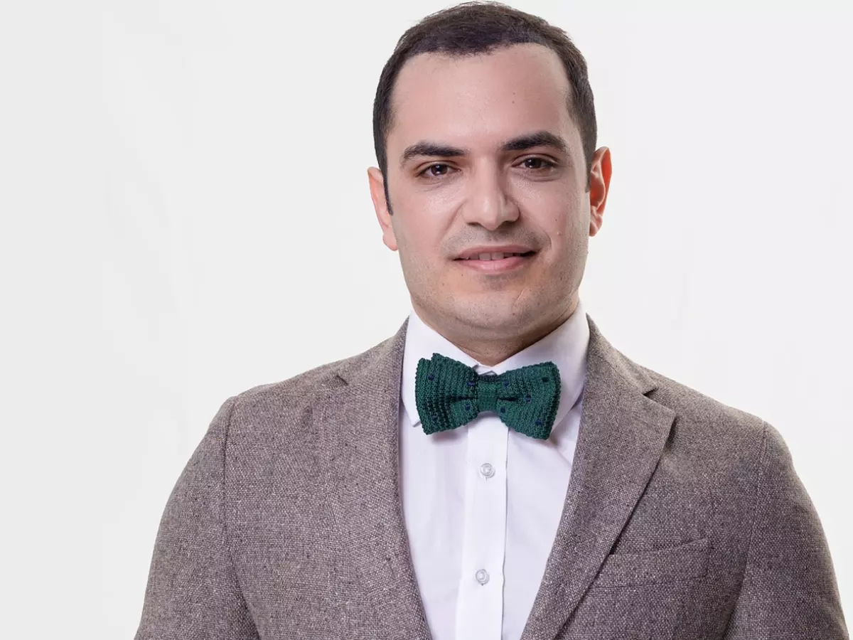 A man in a suit and bow tie smiles at the camera.