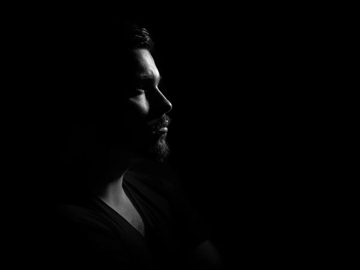 A man's profile in silhouette against a black background.