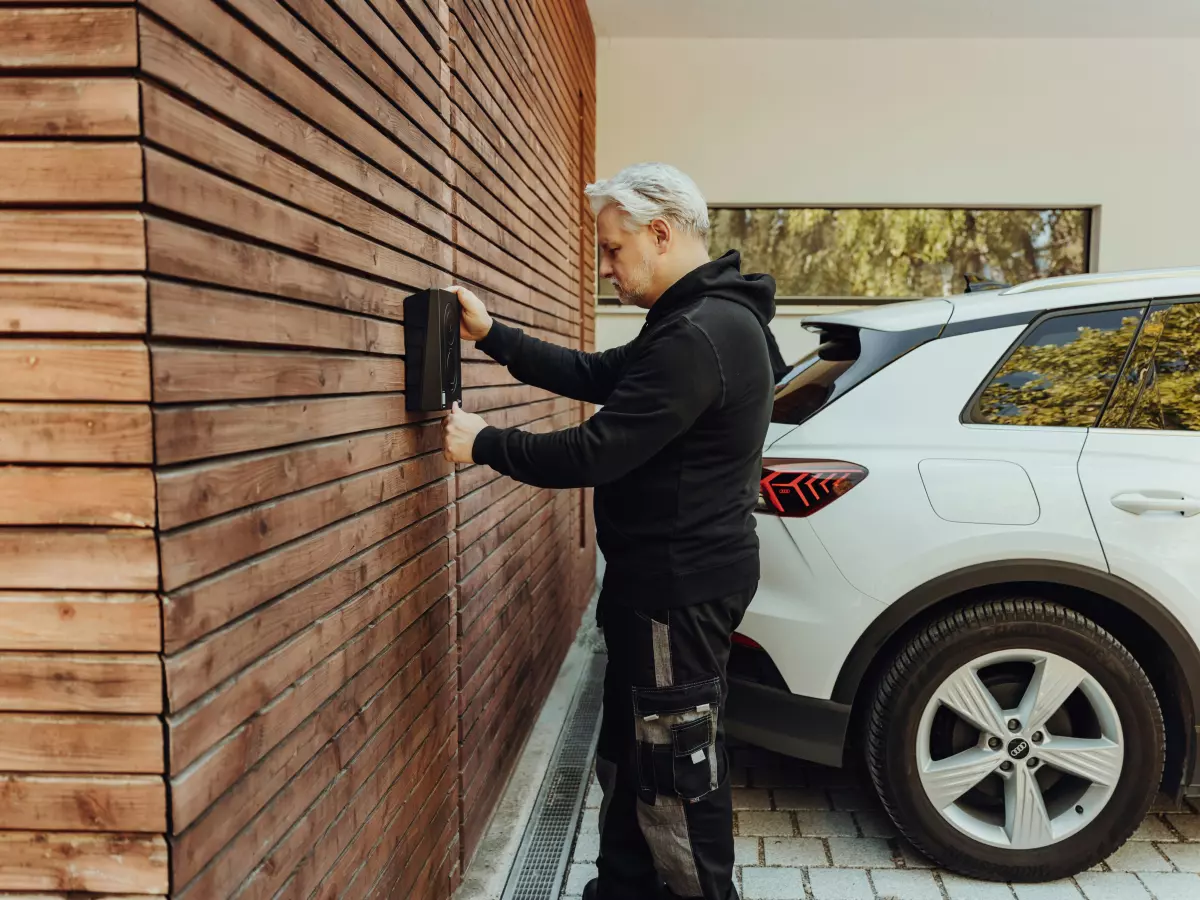 A man plugs a charging cable into an electric car.