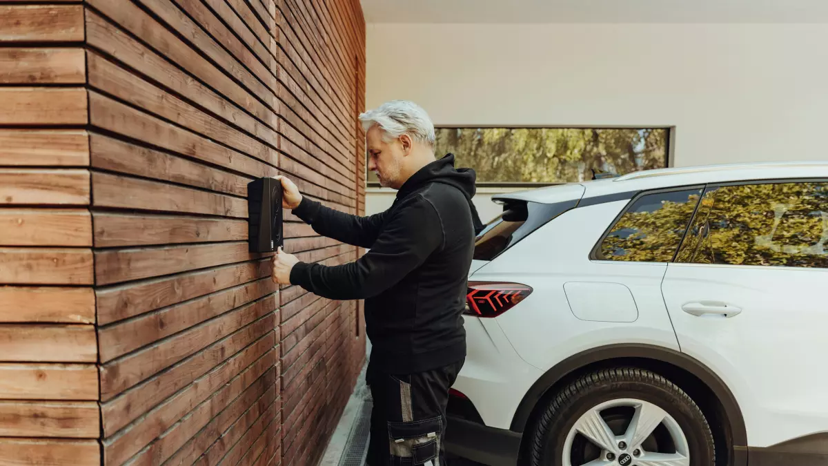 A man plugs a charging cable into an electric car.