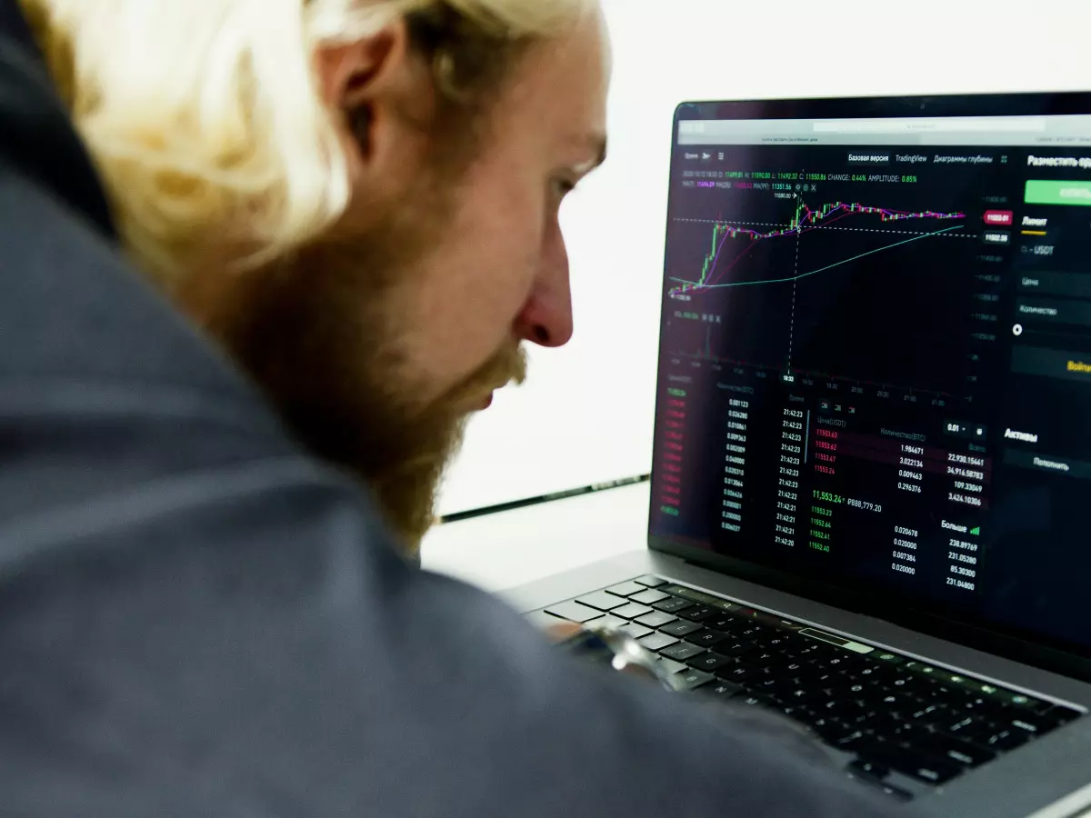 A person looking at a laptop screen with stock charts on it.