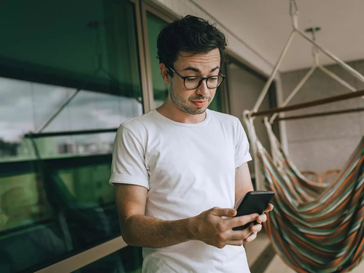 A young man using his smartphone on a balcony