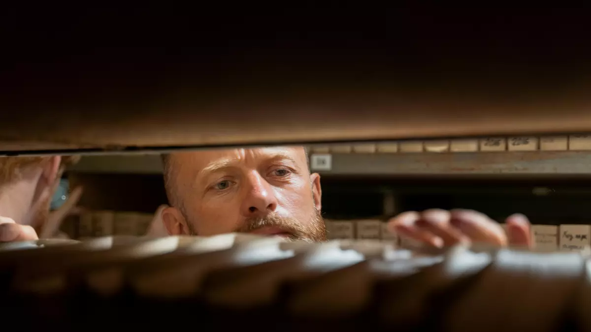 A man is looking down into a server rack, his face is partially obscured by the shadows.