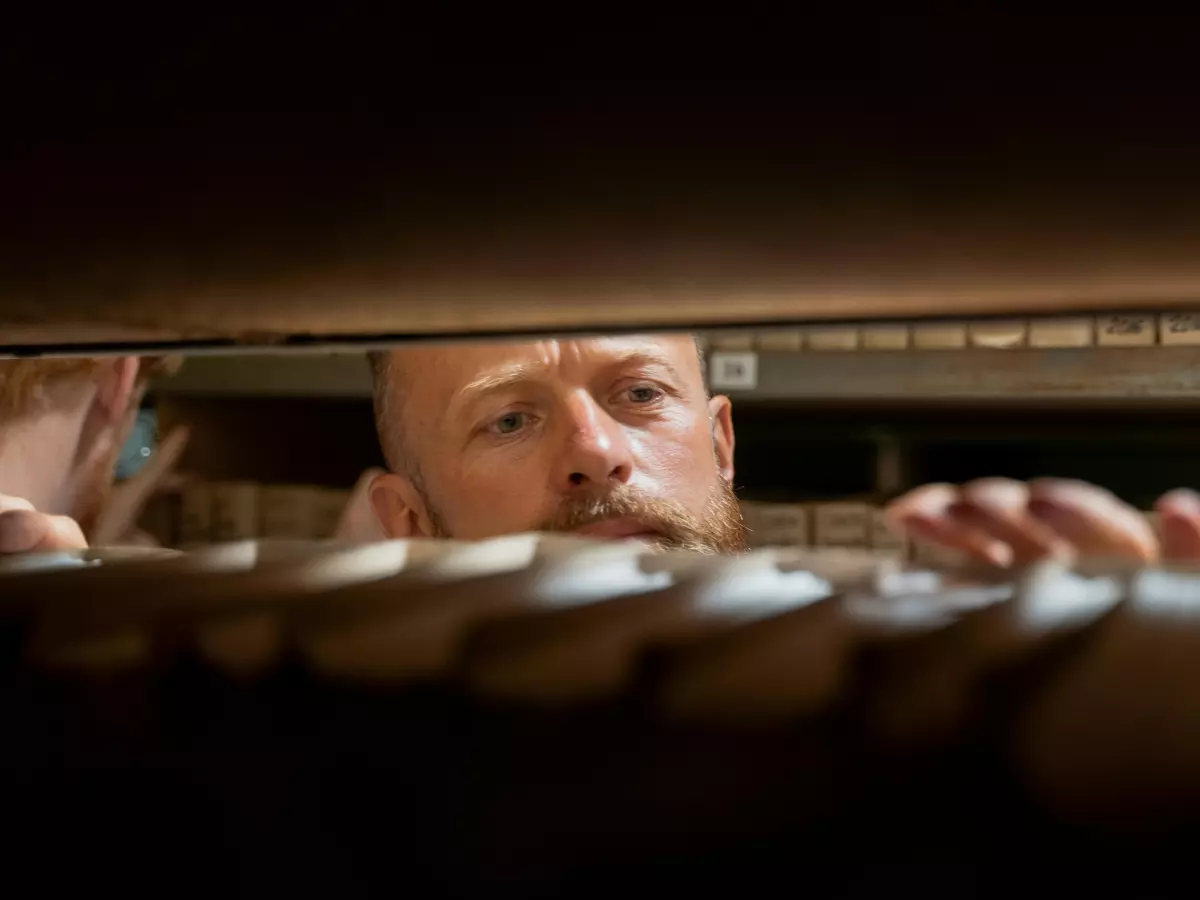 A man is looking down into a server rack, his face is partially obscured by the shadows.