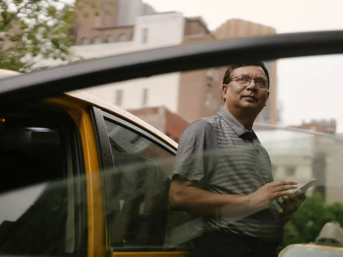 A man is standing in the street with a frustrated look on his face, waiting for a taxi