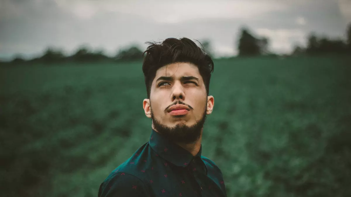 A man with a beard looking up in a field