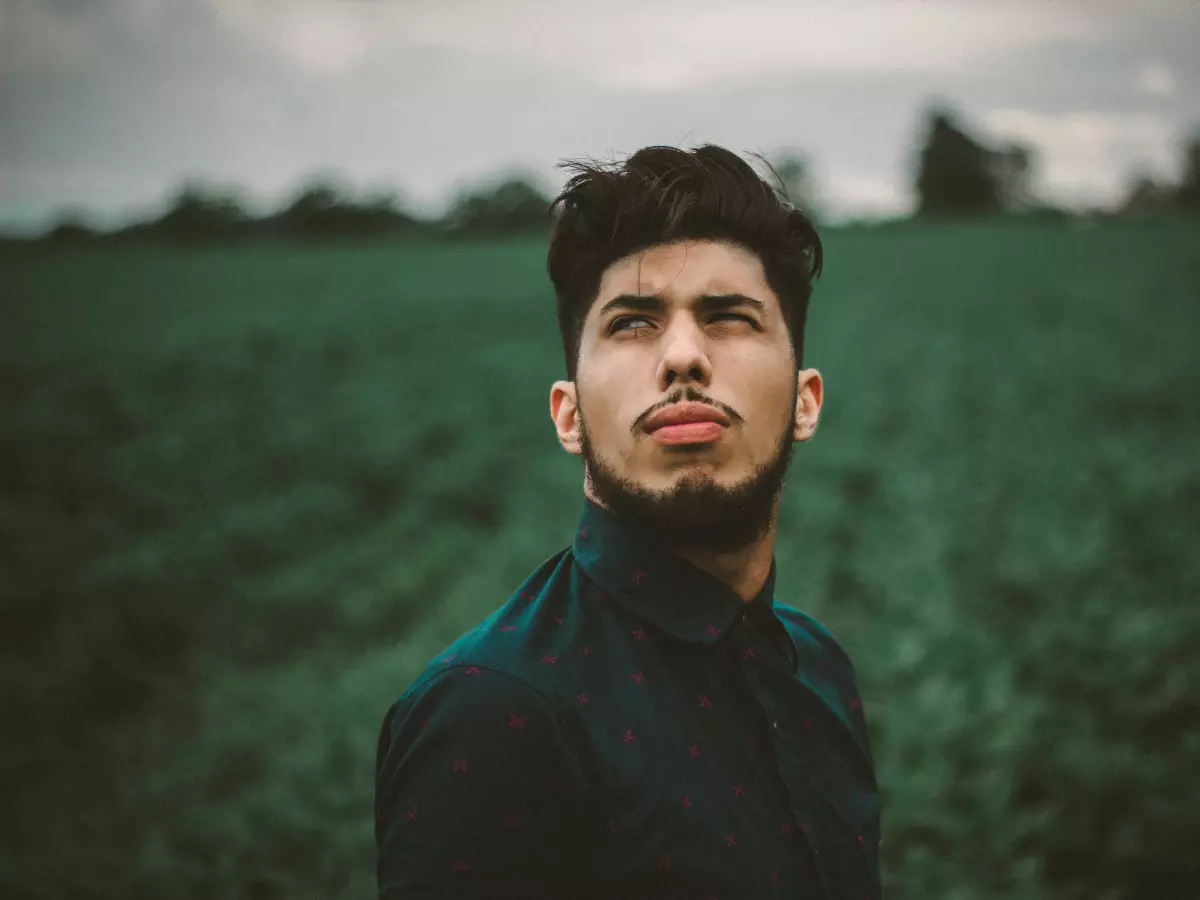 A man with a beard looking up in a field