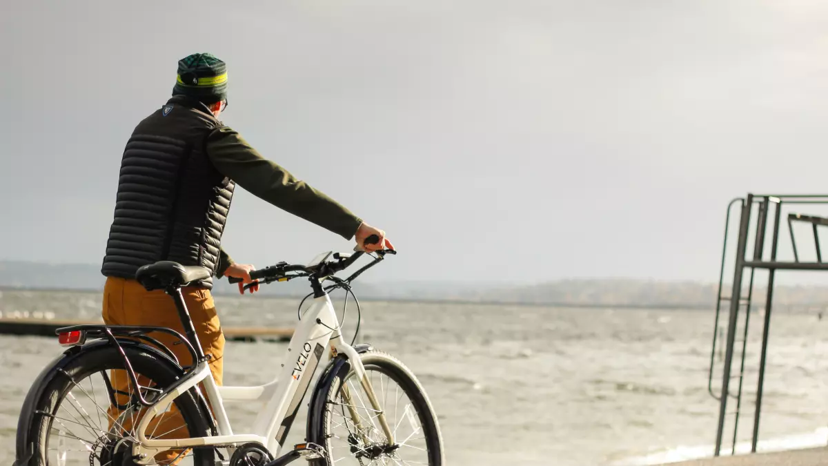 A man riding an electric bike by the sea.