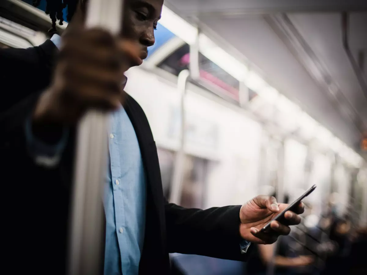 A person is looking at their phone while riding a subway train.