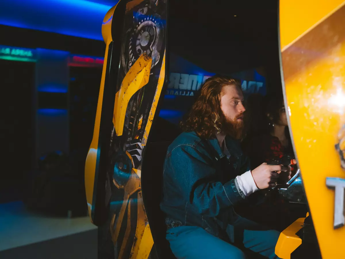 A person holding a transparent gaming controller with blue lighting in a dimly lit room. 