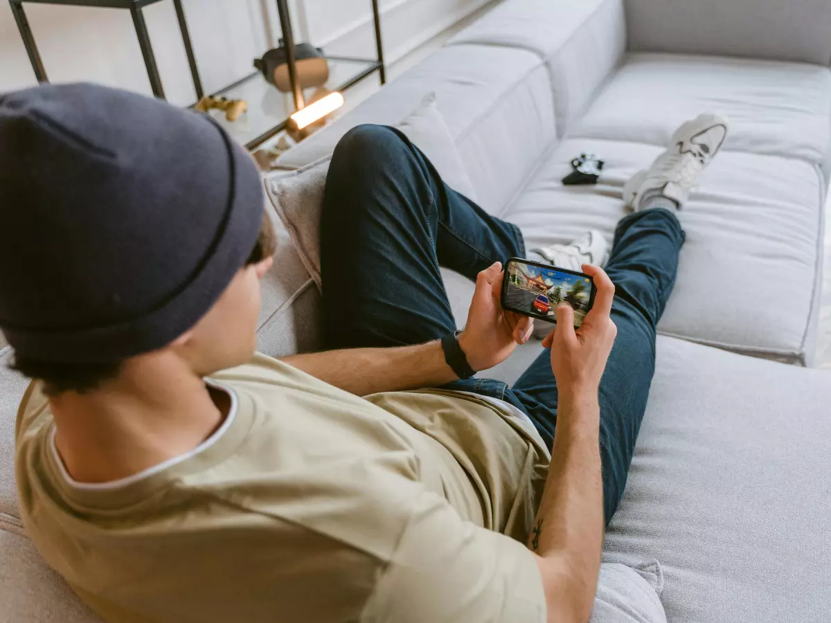 A person is playing a game on their phone, while sitting on a couch. 