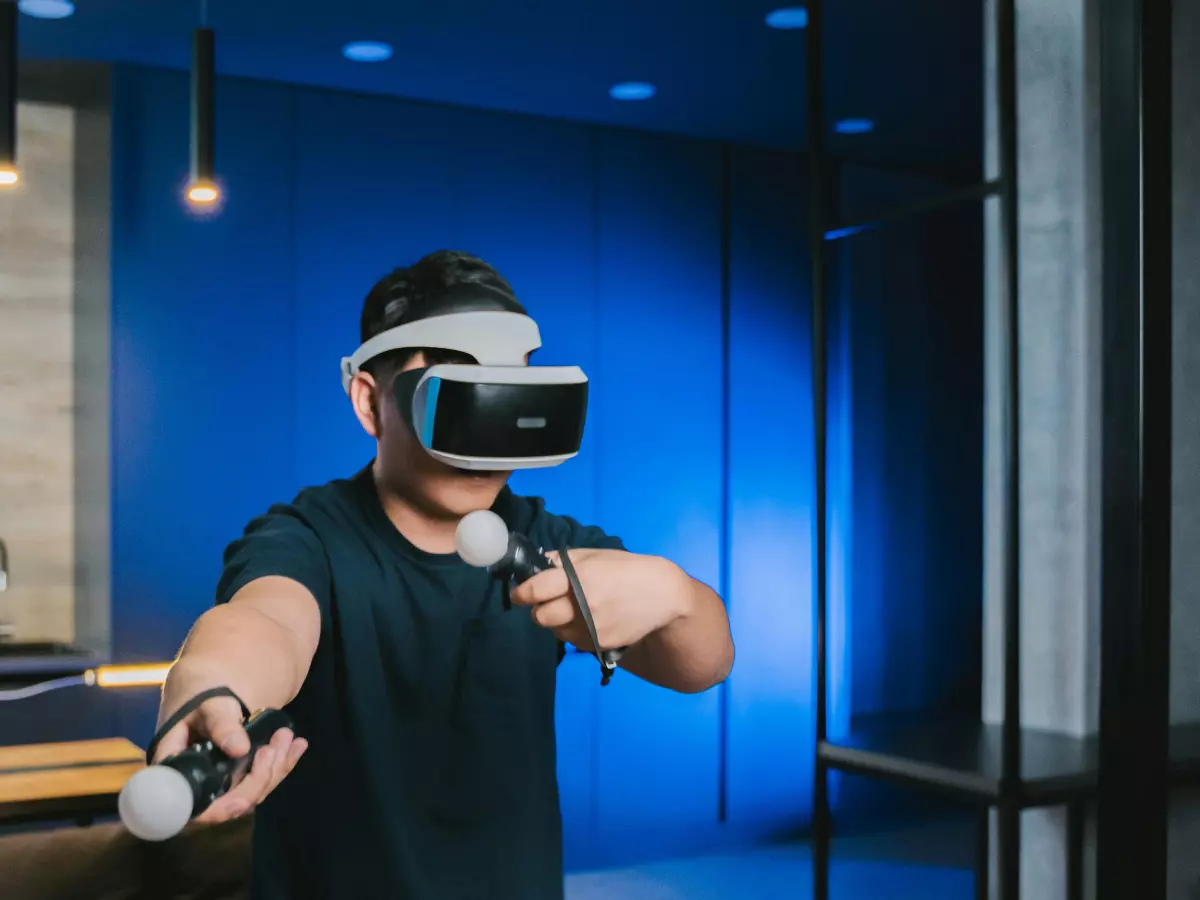 A person wearing a virtual reality headset and holding two controllers.