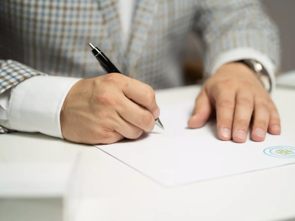 A close-up of a hand signing a document with a pen.