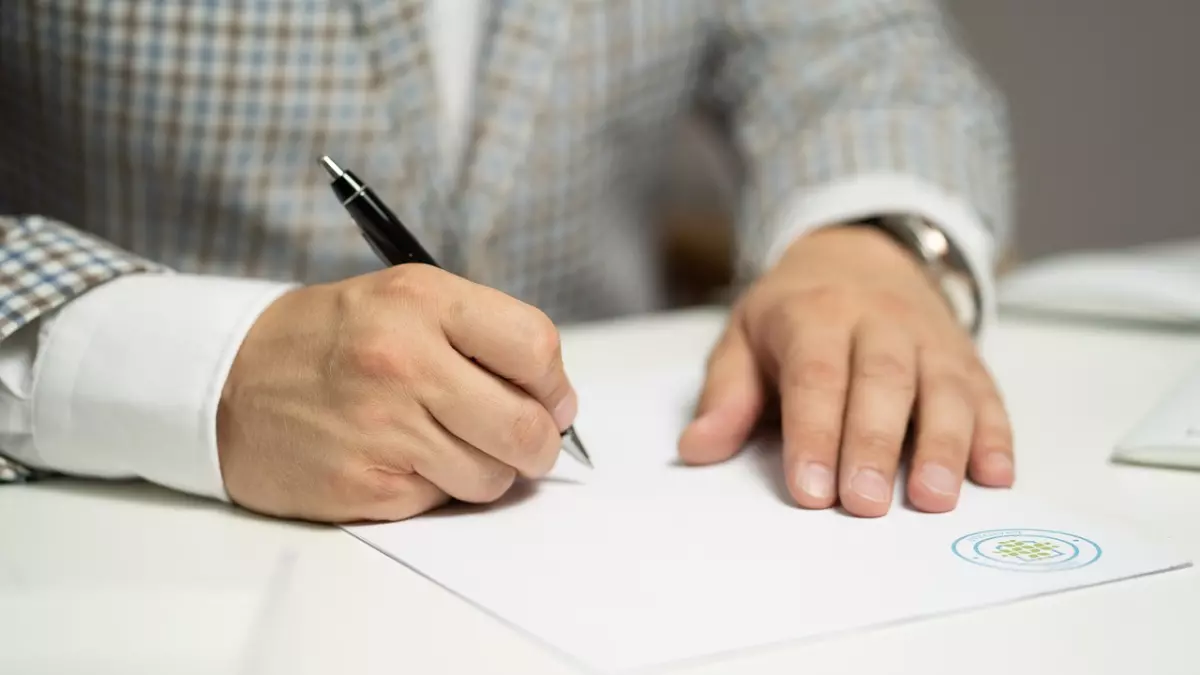 A close-up of a hand signing a document with a pen.