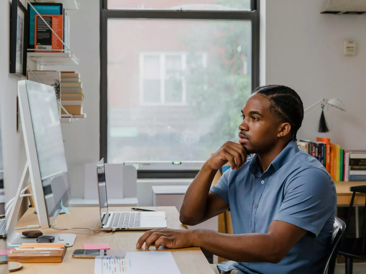 A man is sitting at a desk, staring intently at a computer monitor.