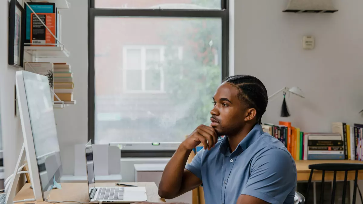 A man is sitting at a desk, staring intently at a computer monitor.