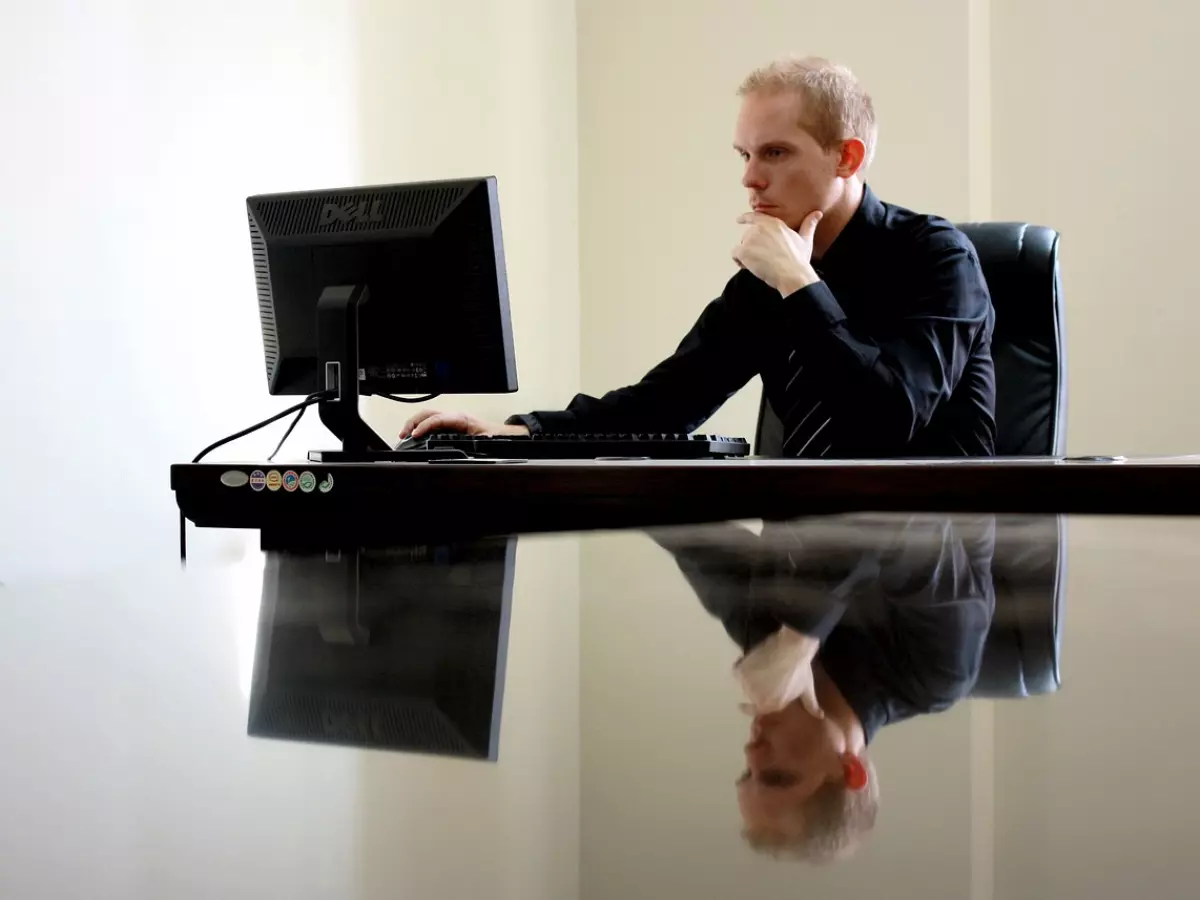 A man in a suit sitting at a desk and working on a computer.