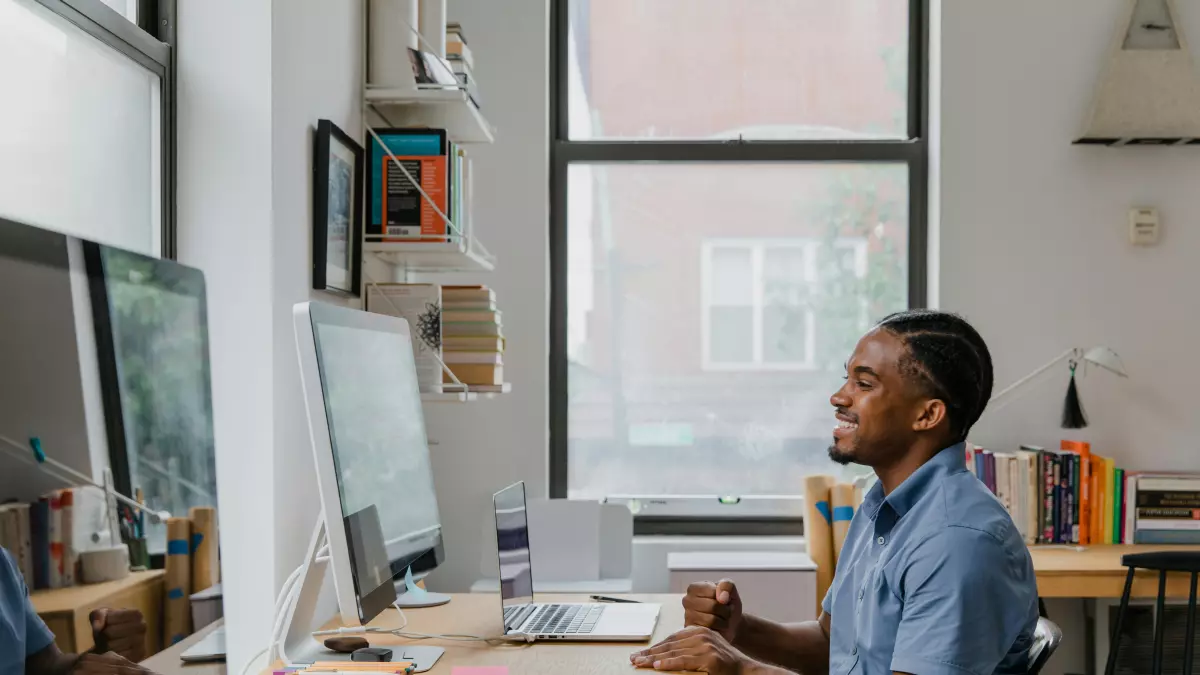 A man sits at a desk in front of a computer, working.