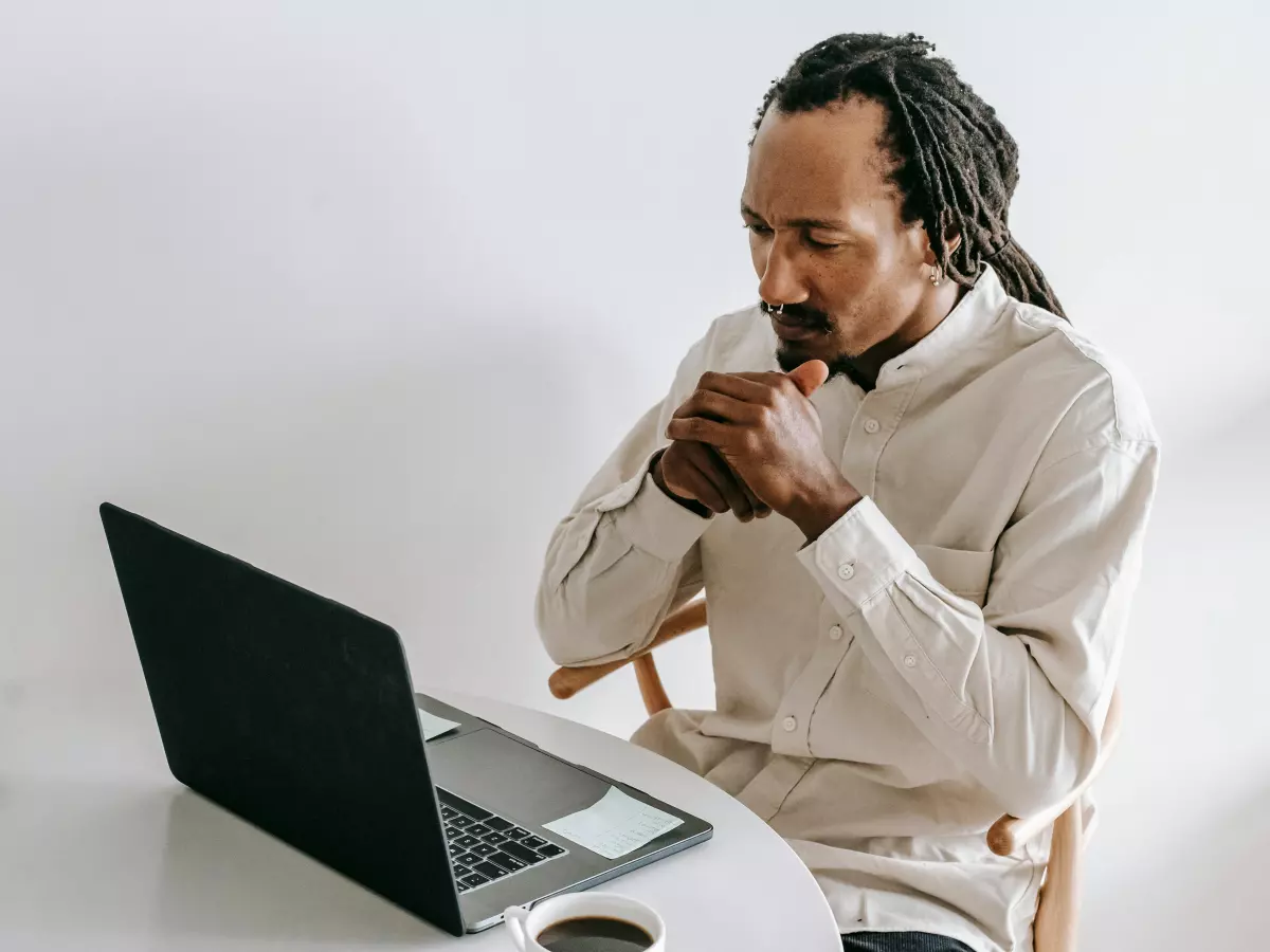 A person sitting at a desk, looking stressed and frustrated, possibly in front of a laptop. The image conveys a sense of urgency and concern, representing the struggle to cope with the consequences of a cyberattack.