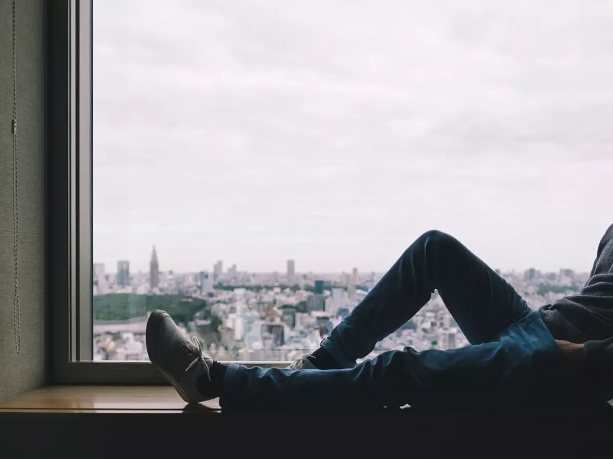 A person is looking out a window with a city view