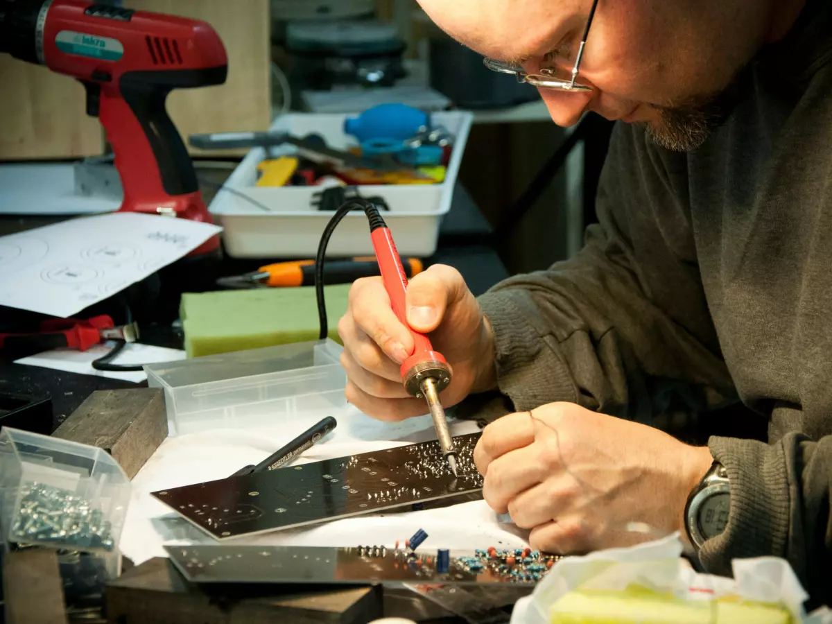 A person soldering a circuit board with a soldering iron.