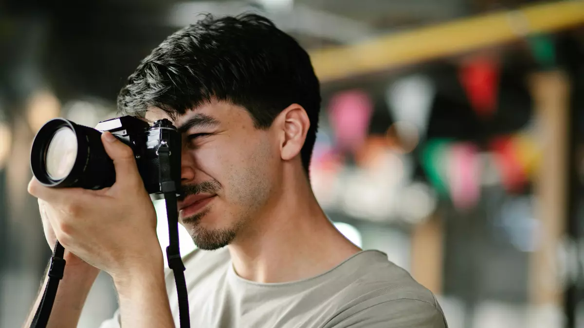 A man is taking a photo with a DSLR camera. The background is out of focus.