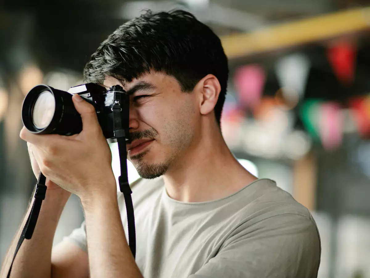 A man is taking a photo with a DSLR camera. The background is out of focus.