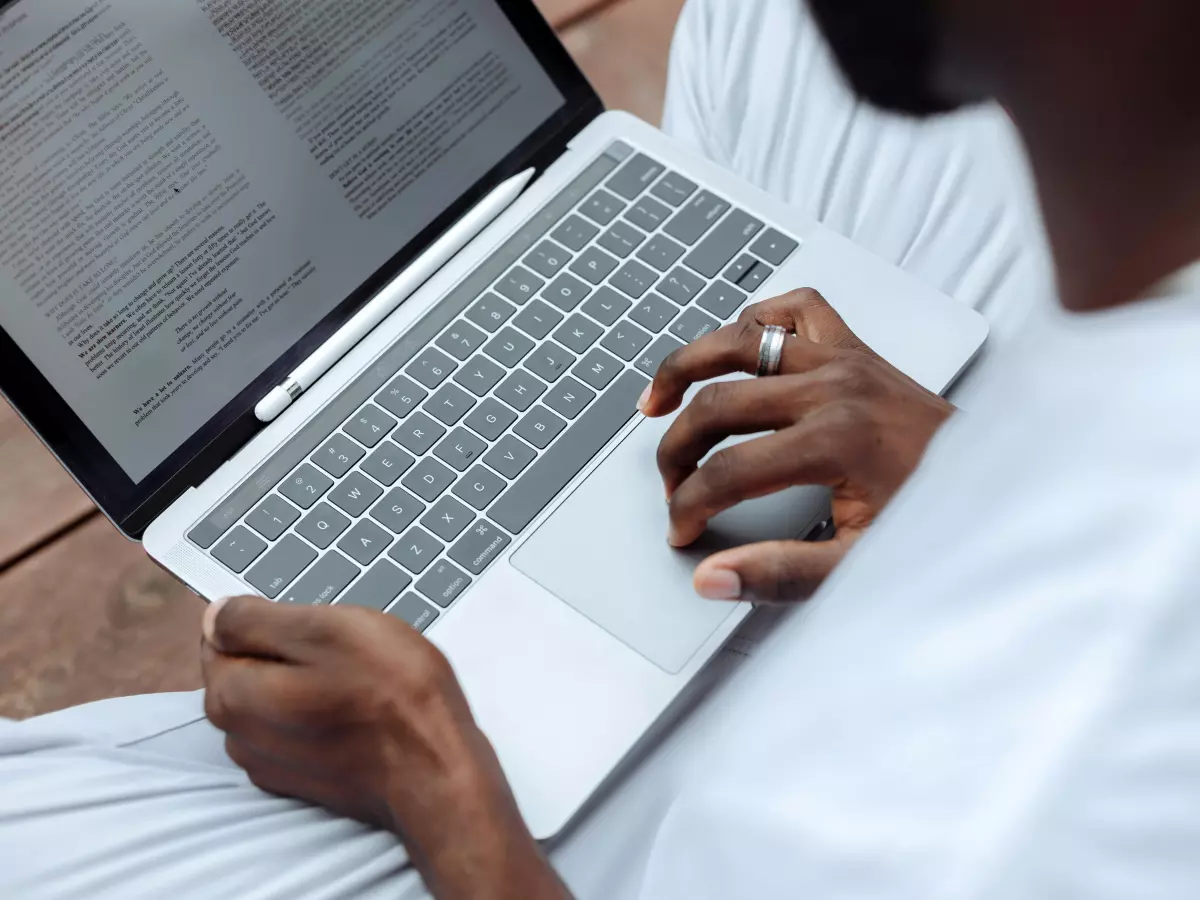 A person is sitting on a bench outside, working on a laptop.