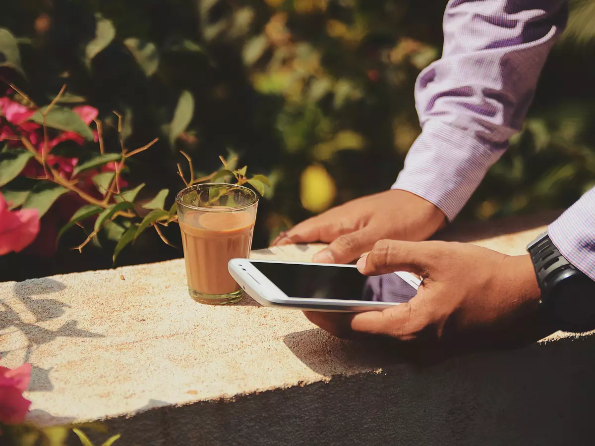 A person sitting on a bench in a park and holding a smartphone in their hand