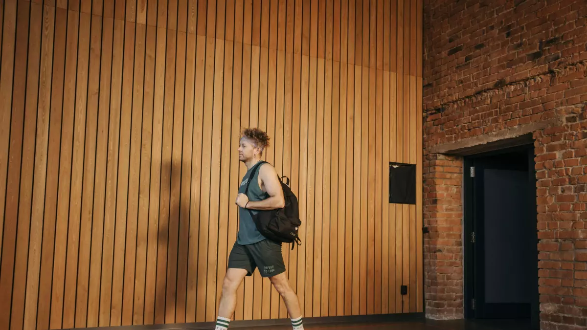 A person wearing a smartwatch and shoes with sensors, walking towards a door.