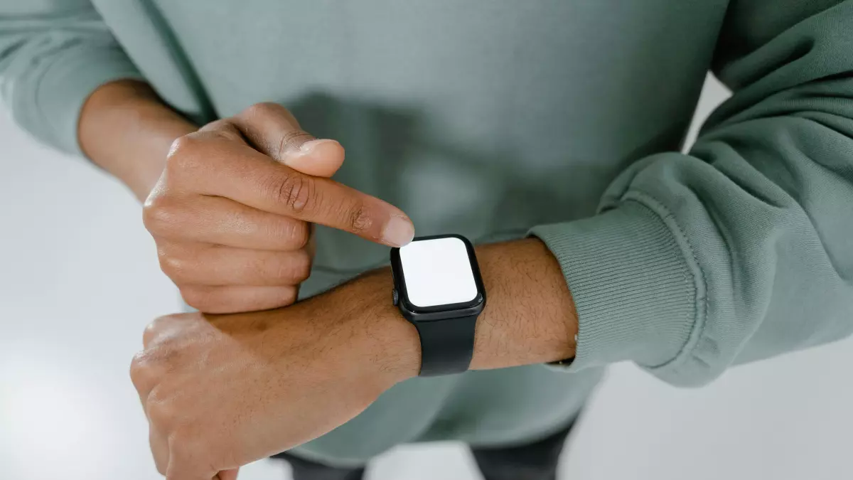 A person wearing a smartwatch, looking at the screen, hands-on,  close-up shot, background blurred. The smartwatch is black with a white screen, and a black strap. The person