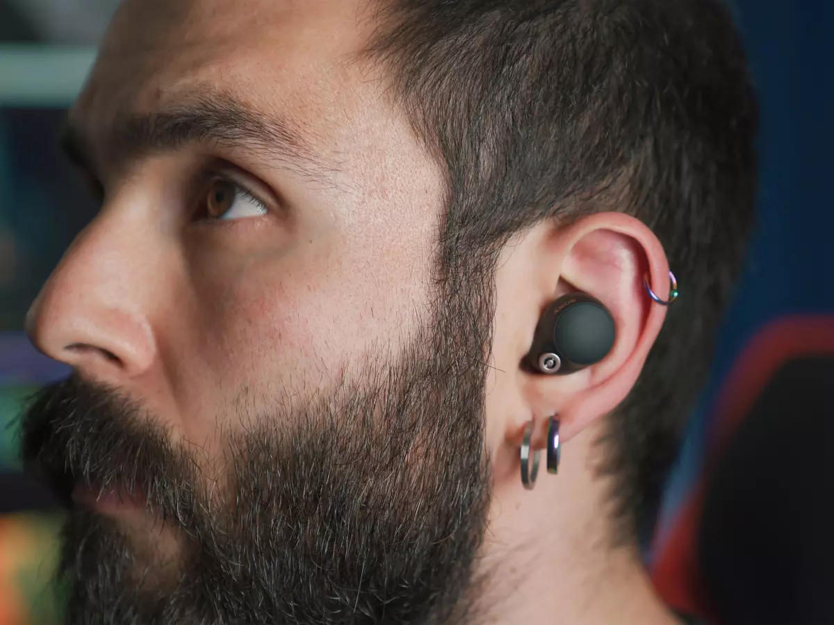 A person with a beard wearing black earbuds