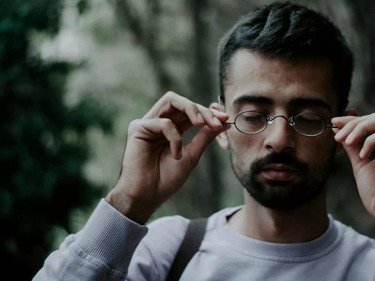 A man with a beard wearing glasses looks down at something.